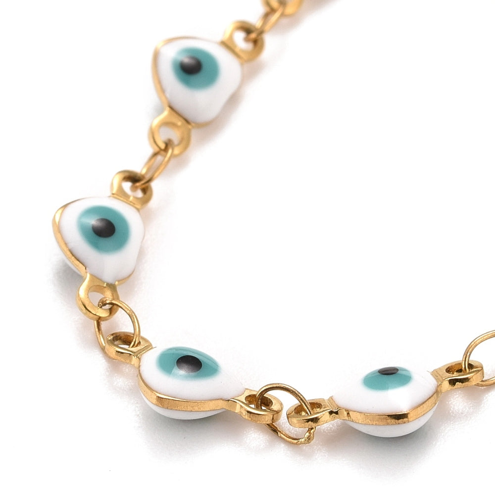 zoomed in section of golden and white enamel heart shaped evil eye bracelet  over white background.