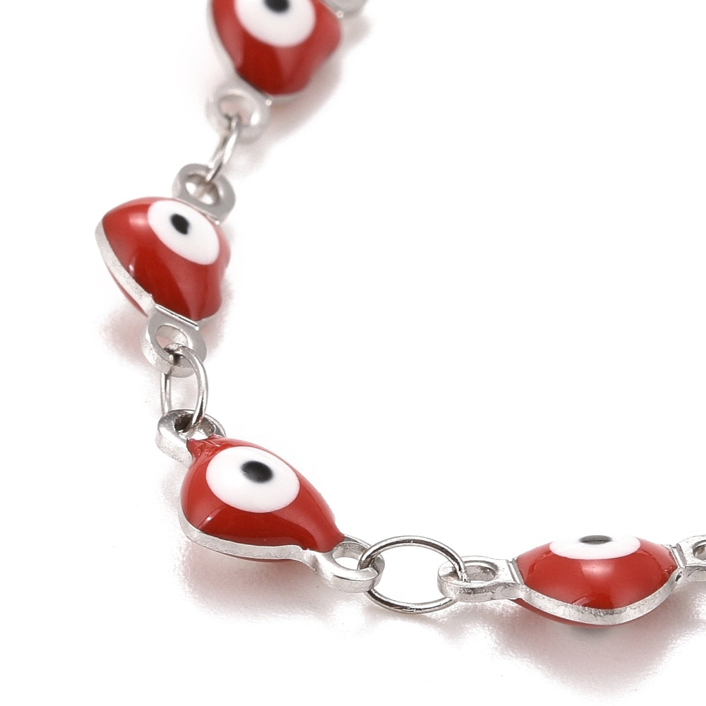 zoomed in section of silver tone and red enamel heart shaped evil eye bracelet  over white background.