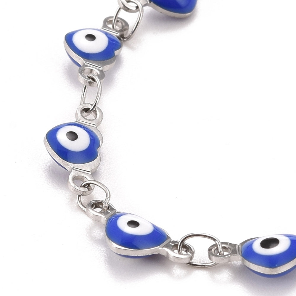zoomed in section of silver tone and blue enamel heart shaped evil eye bracelet with lobster claw clasp and extender chain over white background.