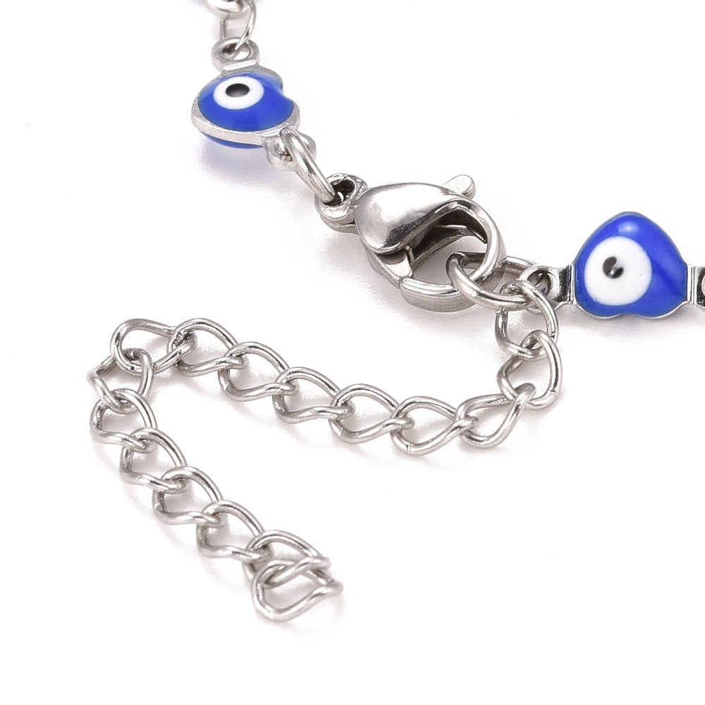 zoomed in section of silver tone and blue enamel heart shaped evil eye bracelet over white background.