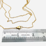 golden fine flat cable chain necklace with lobster claw clasp above a silver imperial ruler on a white background. 