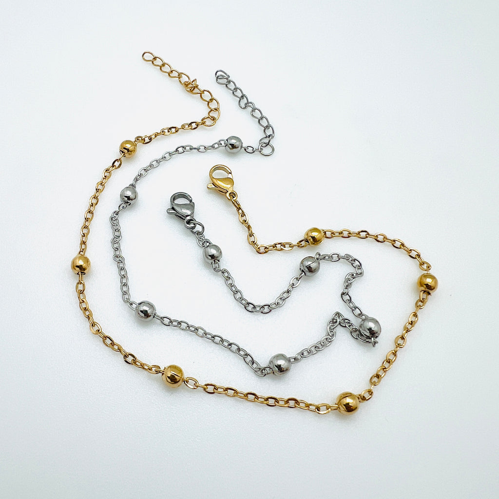 golden and silver tone satellite chain anklets with lobster claw clasp and extender chain over white background. 