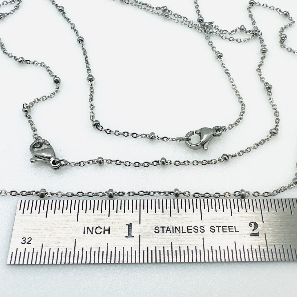 silver tone satellite chain necklace with rondelle beads and lobster claw clasp displayed above ruler with white background.