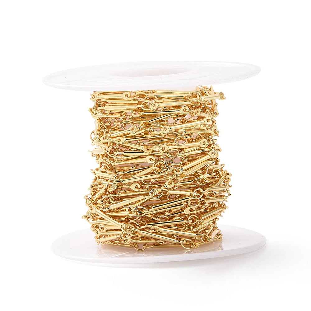 spool of golden bar link chain over white background. 