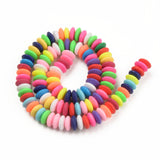 bright multicolor polymer clay saucer bead strand in a swirl design over white background. 