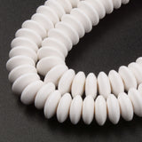 zoomed in sections of white polymer clay saucer bead strands over textured black background. 