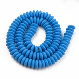 blue polymer clay saucer bead strand in a swirl design over white background. 