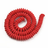 red polymer clay saucer bead strand in a swirl design over white background. 