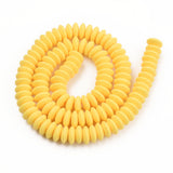 yellow polymer clay saucer bead strand in a swirl design over white background. 