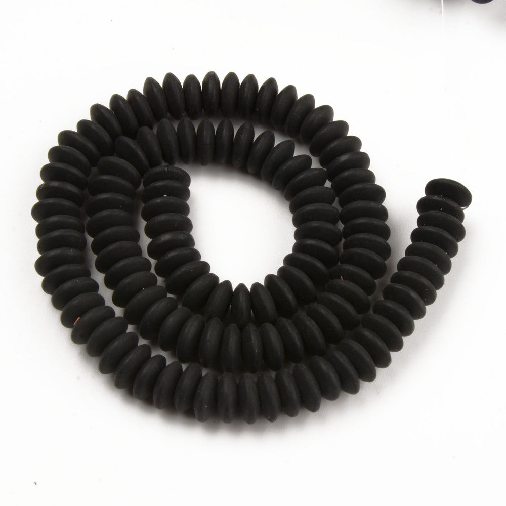 black polymer clay saucer bead strand in a swirl design over white background. 