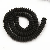 black polymer clay saucer bead strand in a swirl design over white background. 