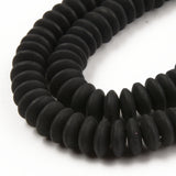 zoomed in sections of black polymer clay saucer bead strands over white background. 