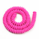 fuchsia polymer clay saucer bead strand in a swirl design over white background. 