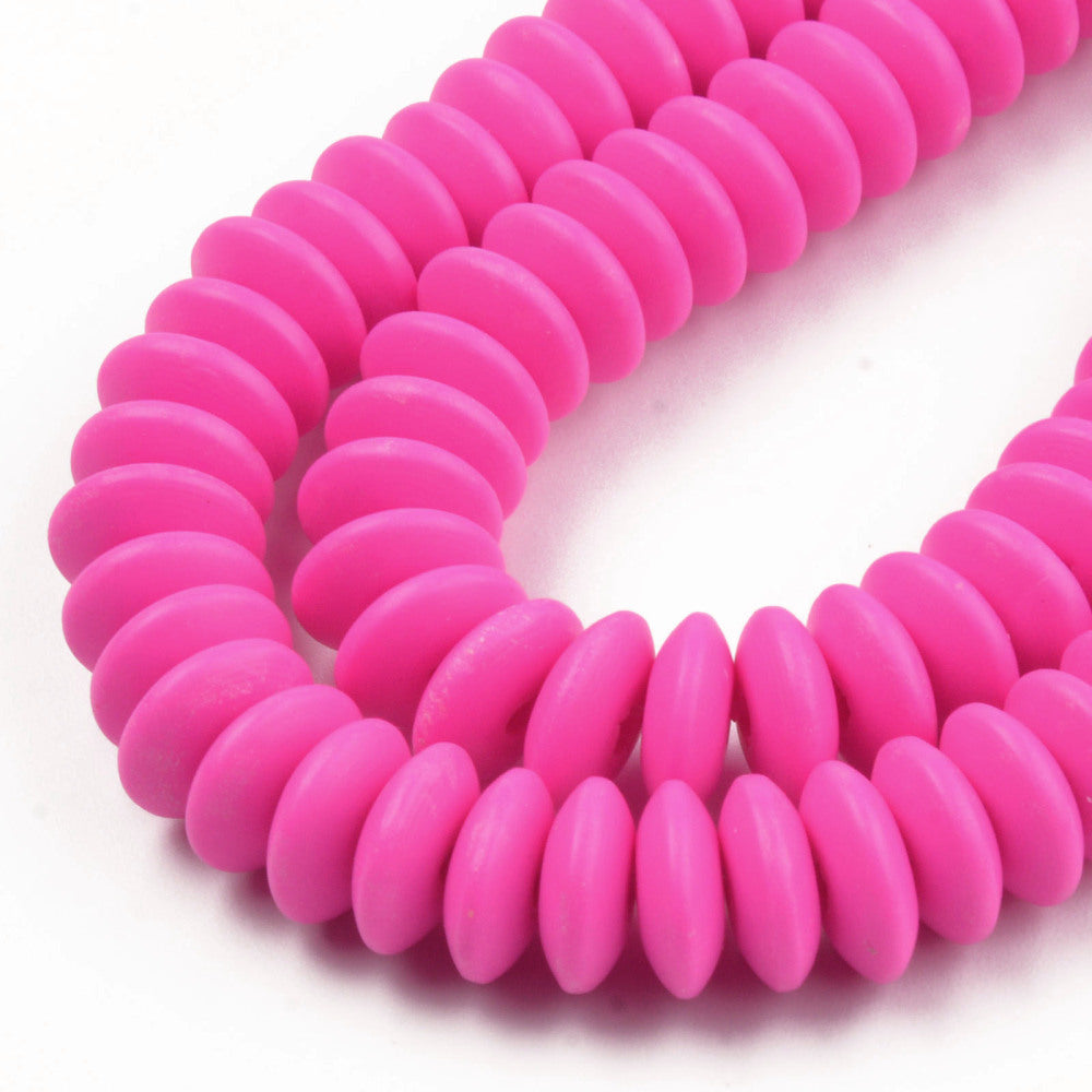 zoomed in sections of fuchsia polymer clay saucer bead strands over white background. 