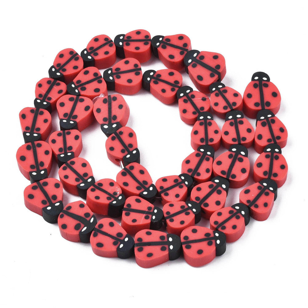 red polymer clay ladybug bead strand in swirl design over white background. 