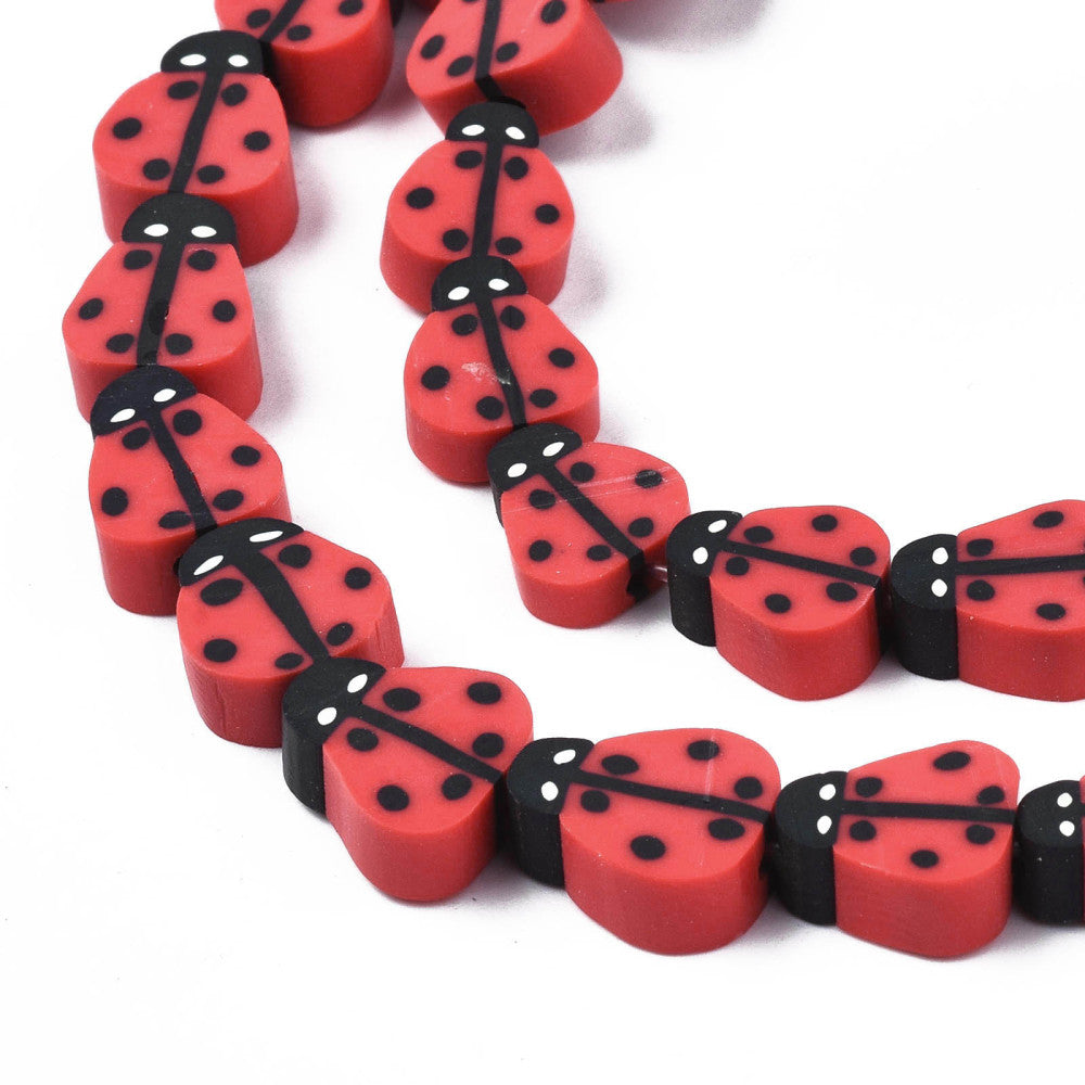 zoomed in sections red polymer clay ladybug bead strands over white background. 