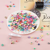 light pink surface with a white dish containing most of the bright and adorable beads from the kit while some have spilled onto the surface and some others are strung on elastic cord and a spool of the black cord included in the kit is in the top right corner. 