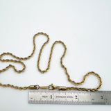 golden rope chain with lobster claw clasp above stainless steel imperial ruler  on white background. 