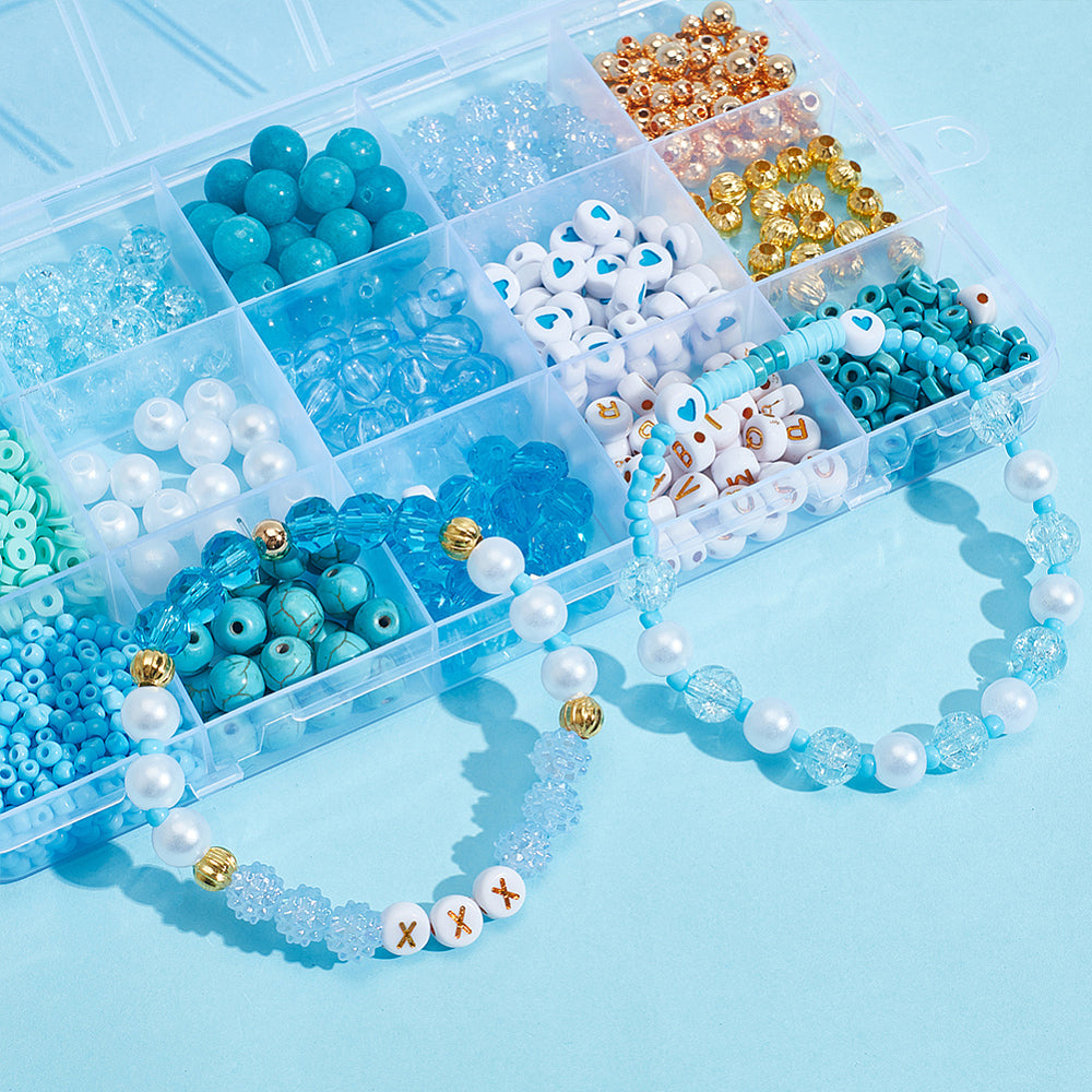 view of three quarters of the box of blue and gold beads with two strung bracelet samples draped over the open box onto the light blue surface.