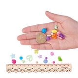 a hand holding a dollar coin along with some samples of loose beads and some displayed above a wooden ruler with white background. 