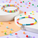examples of some friendship bracelets made with some of the rainbow beads on white pedestals as well as some loose beads all over the light orange and purple surface. 
