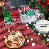 fifteen compartment bead box featuring an assorted variety of Christmas-themed beads with a spool of crystal string and loose examples below the box on a red and green surface or on a slice of wood. 
