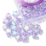 corner of plastic bead box with iridescent light purple heart star and round beads spilling out onto white surface. 