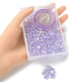 plastic bead box with iridescent light purple transparent beads and spool of purple stretch cord in a mannequin hand with a small pile below of loose beads on white surface. 