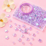 plastic bead box with iridescent light purple transparent beads and spool of purple stretch cord with some loose heart star and round beads spilled out onto pink surface with cream colored flowers in the corner. 