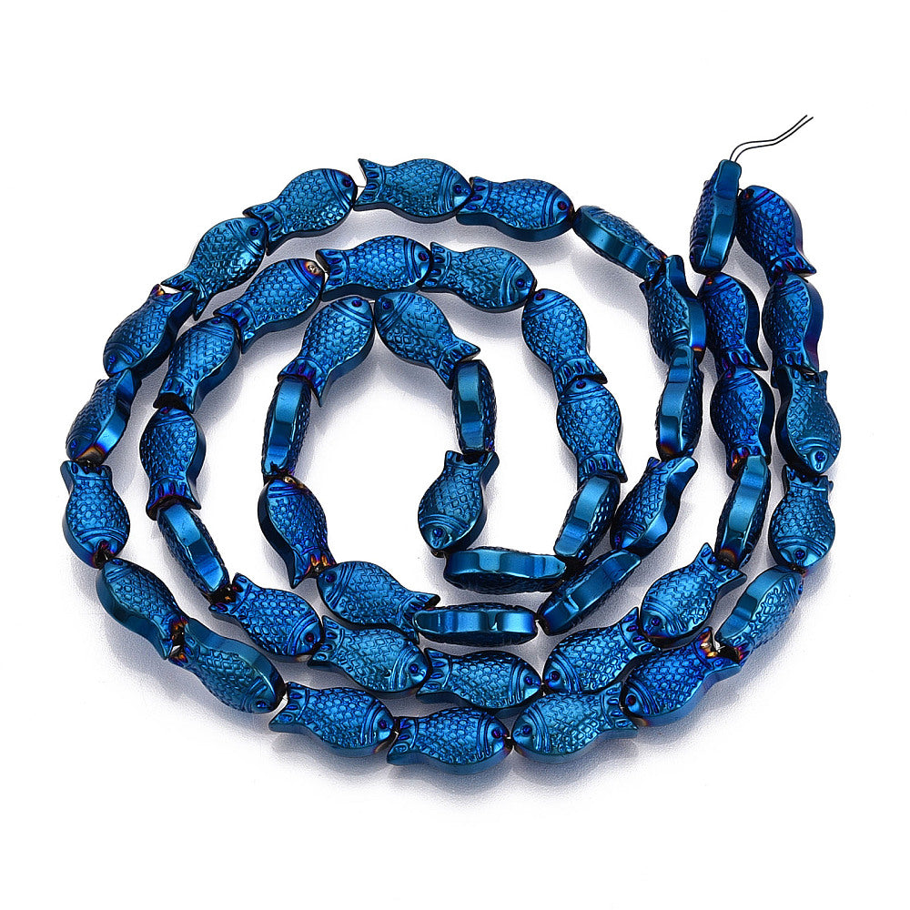 blue electroplate glass fish bead strand in swirl design over white surface. 