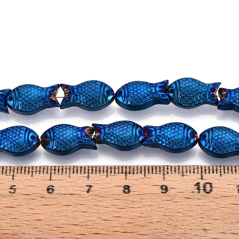 zoomed in sections of blue electroplate glass fish bead strands displayed over a wooden ruler and white surface. 