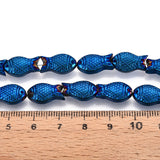 zoomed in sections of blue electroplate glass fish bead strands displayed over a wooden ruler and white surface. 