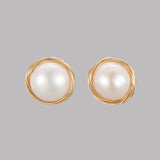 large white freshwater pearl stud earrings with golden wire wrapped "nest" surrounding pearl over grey background. 