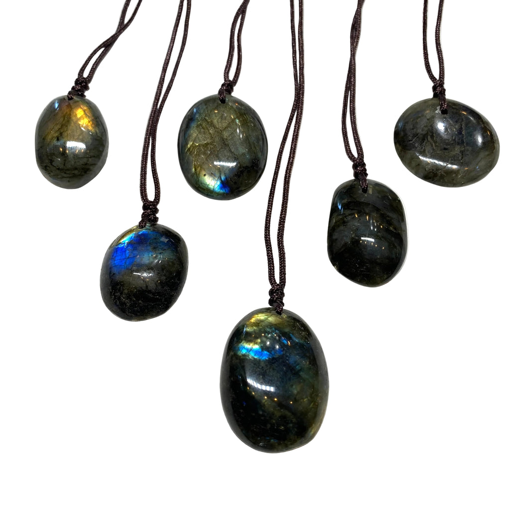 six unique labradorite stone pendants each strung on brown cord over a white background. 