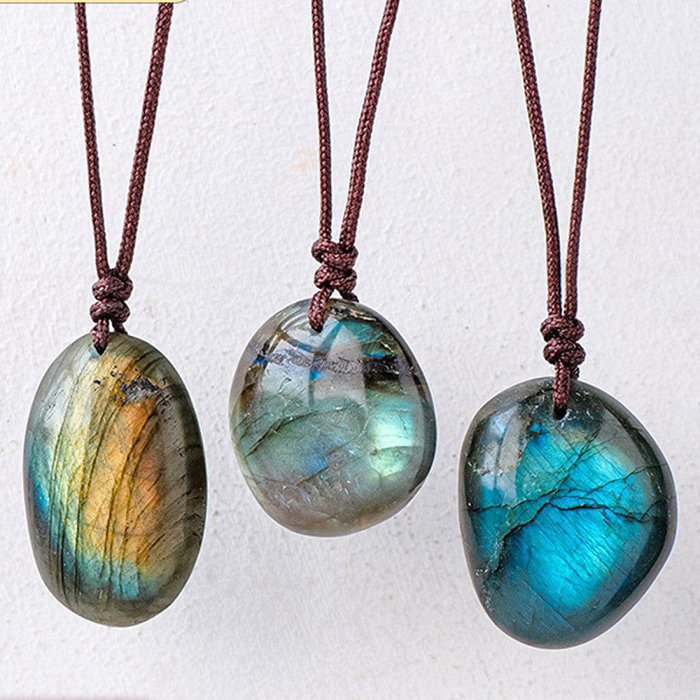 three unique labradorite stone pendants each strung on brown cord over a white background. 
