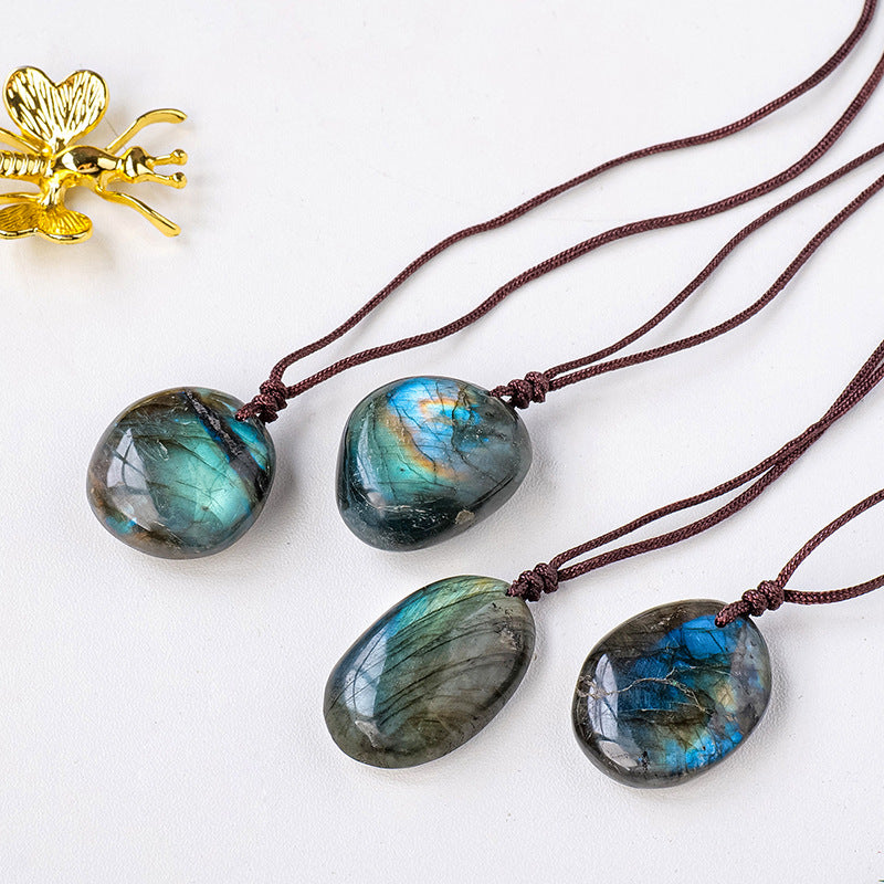 four unique labradorite stone pendants each strung on brown cord with a golden insect sculpture above all over a white background. 