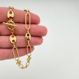 golden alternating paperclip link and coffee bean link chain necklace with toggle clasp displayed on a hand with white background. 