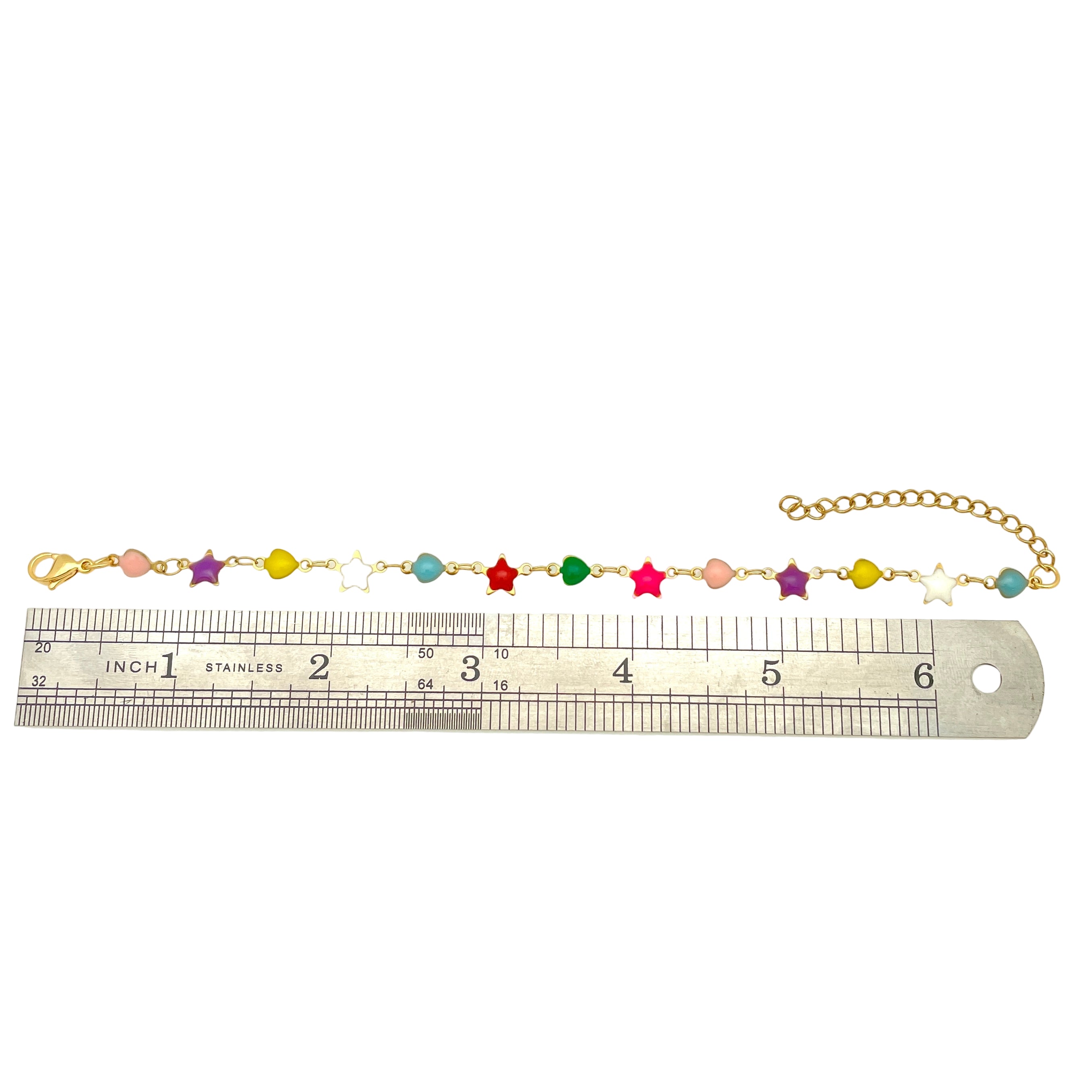golden multi-colored enamel heart and star link bracelet with lobster claw clasp and extender chain displayed over ruler with white background. 