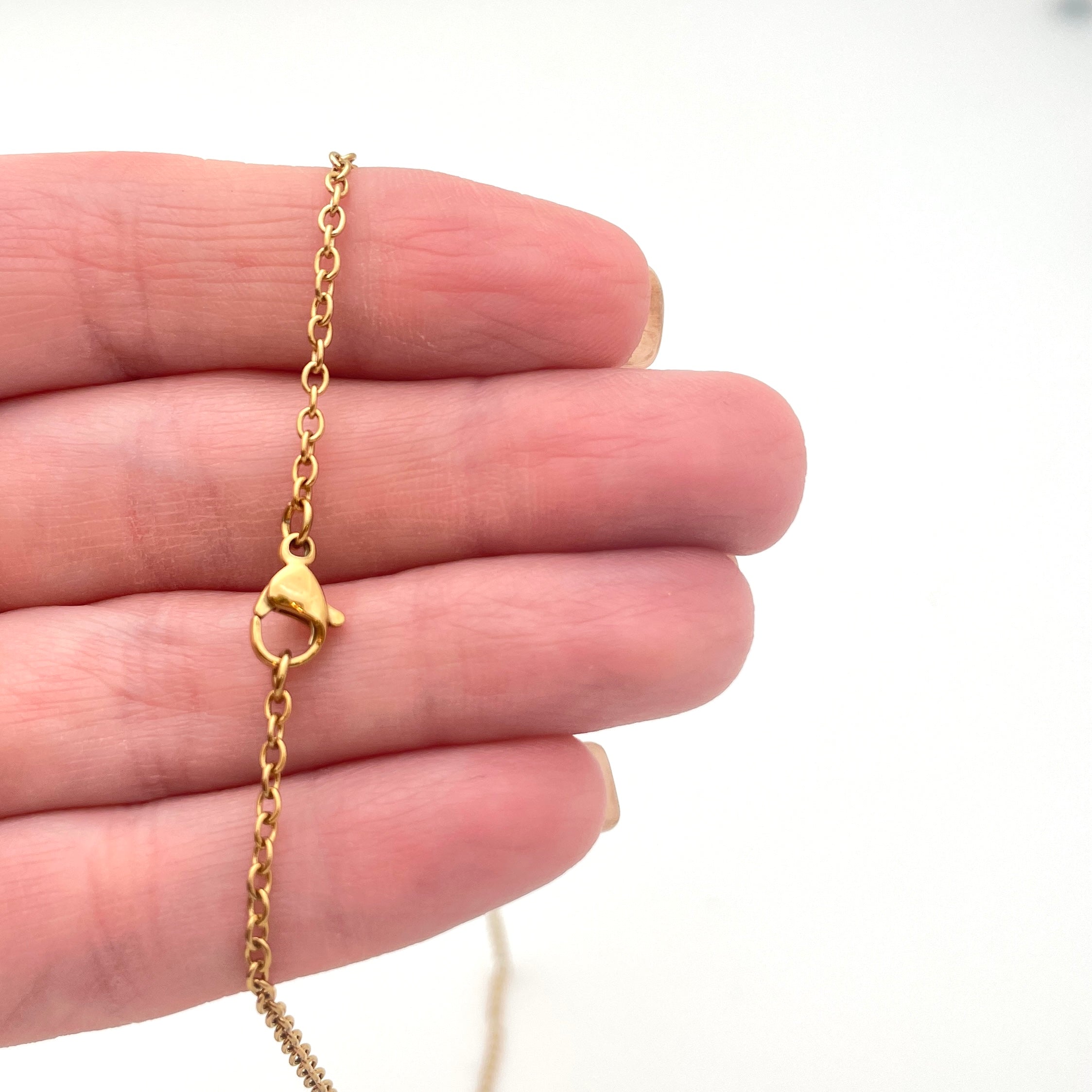 stainless steel cable chain with lobster claw clasp displayed on hand with white background. 
