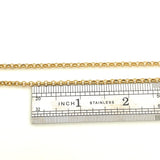 golden medium Rolo chain necklace above stainless steel imperial ruler on white background. 
