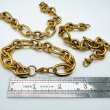 3 golden, large alternating oval and round link chain bracelet with lobster claw clasp above stainless steel imperial ruler on white background. 