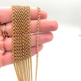 multiple golden medium Rolo chain necklaces on a hand on white background. 