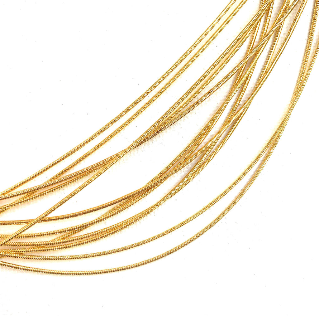 zoomed in sections of many golden snake chain on white background. 