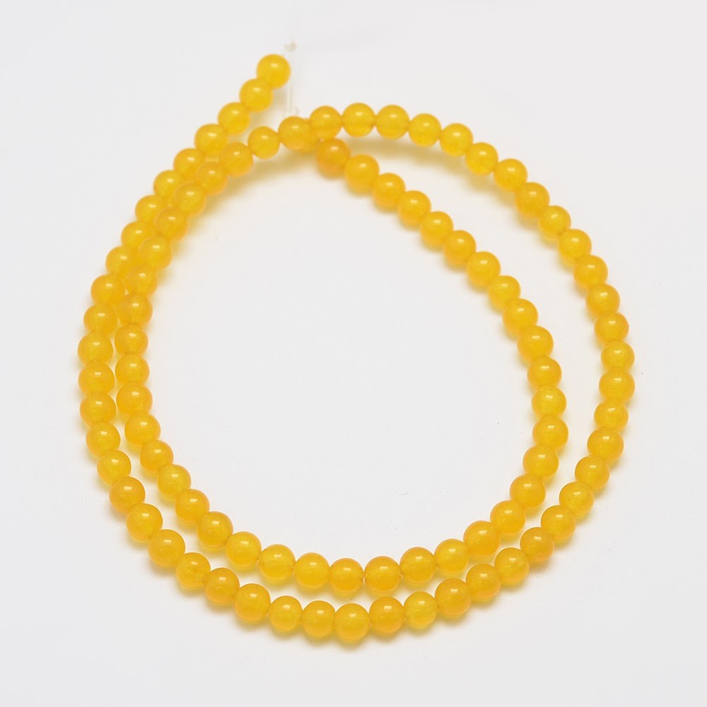 smooth, round, translucent, dyed dark yellow jade bead strand in swirl design over white surface. 