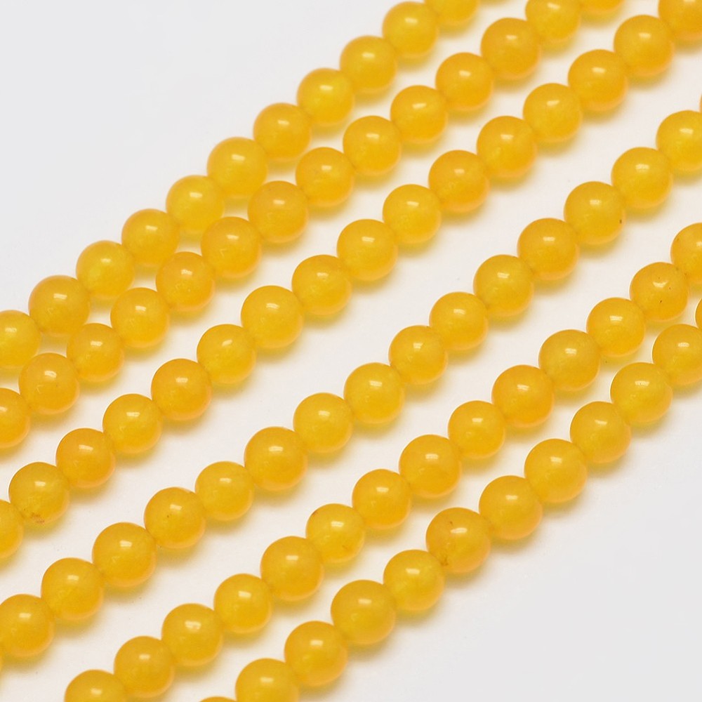 zoomed in sections of smooth, round, translucent, dyed dark yellow jade bead strands over white surface. 