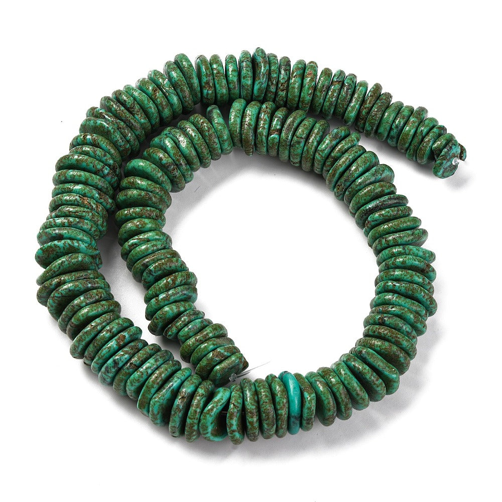 coconut dark green, synthetic turquoise graduated bead strand in swirl design over white surface. 