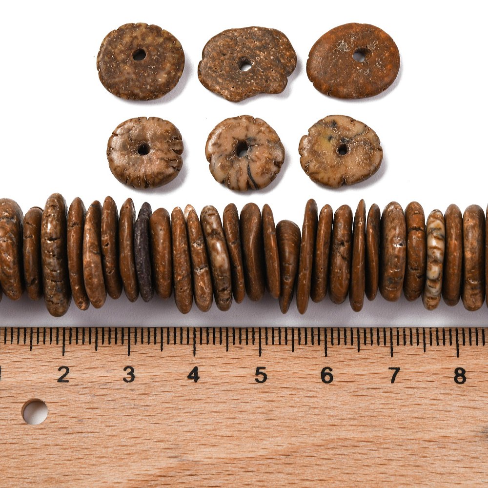coconut brown dyed, synthetic turquoise graduated bead strand with six loose beads above and a wooden ruler below all on a white surface.