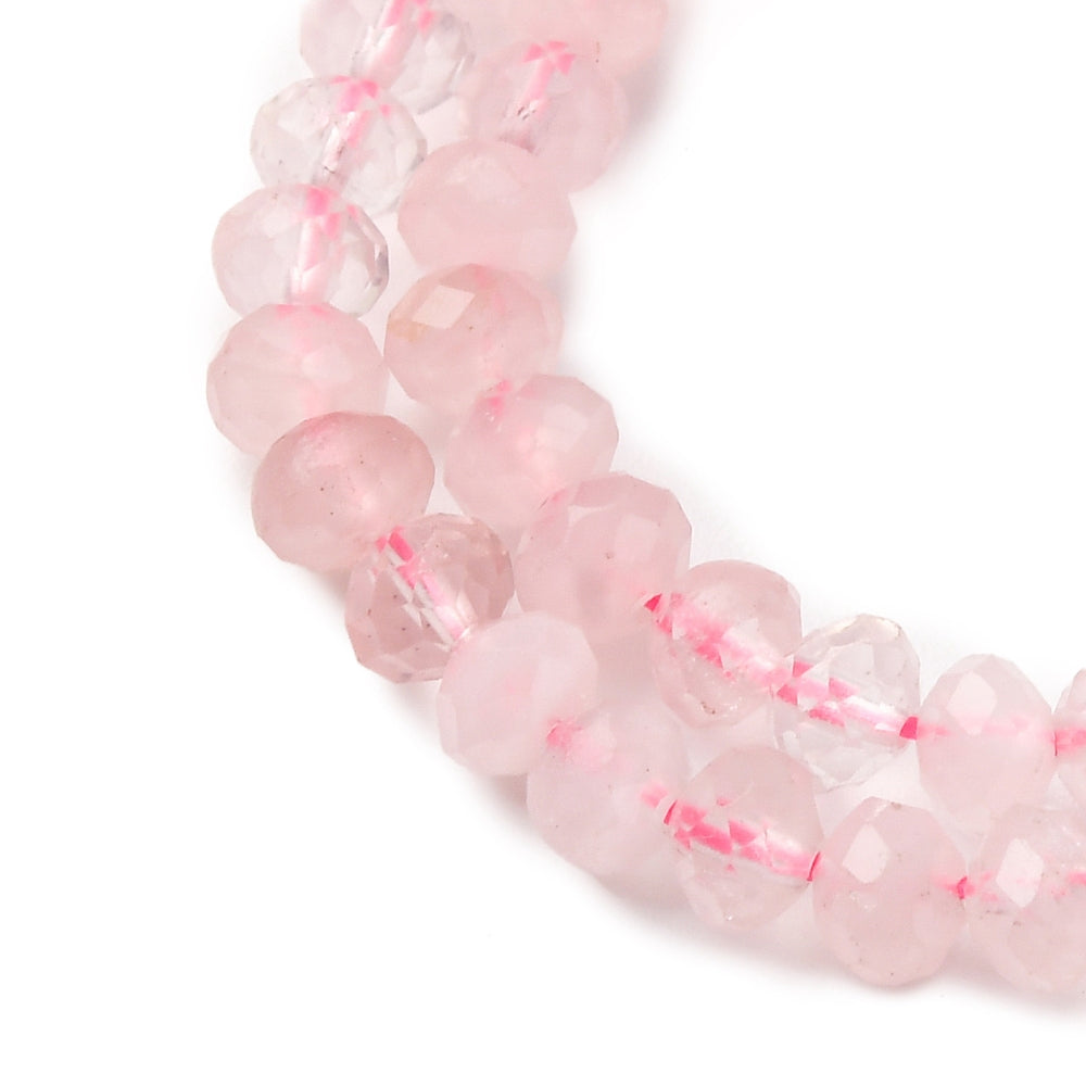 close-up of faceted rondelle rose quartz bead strand over white background. 