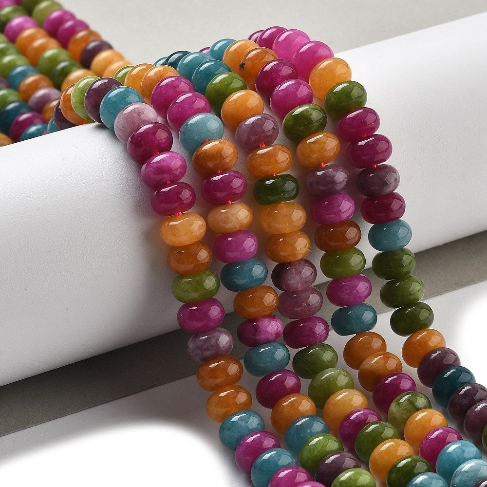 8mm mixed jewel tone smooth rondelle bead strands draped over white cylinder form onto white surface. 