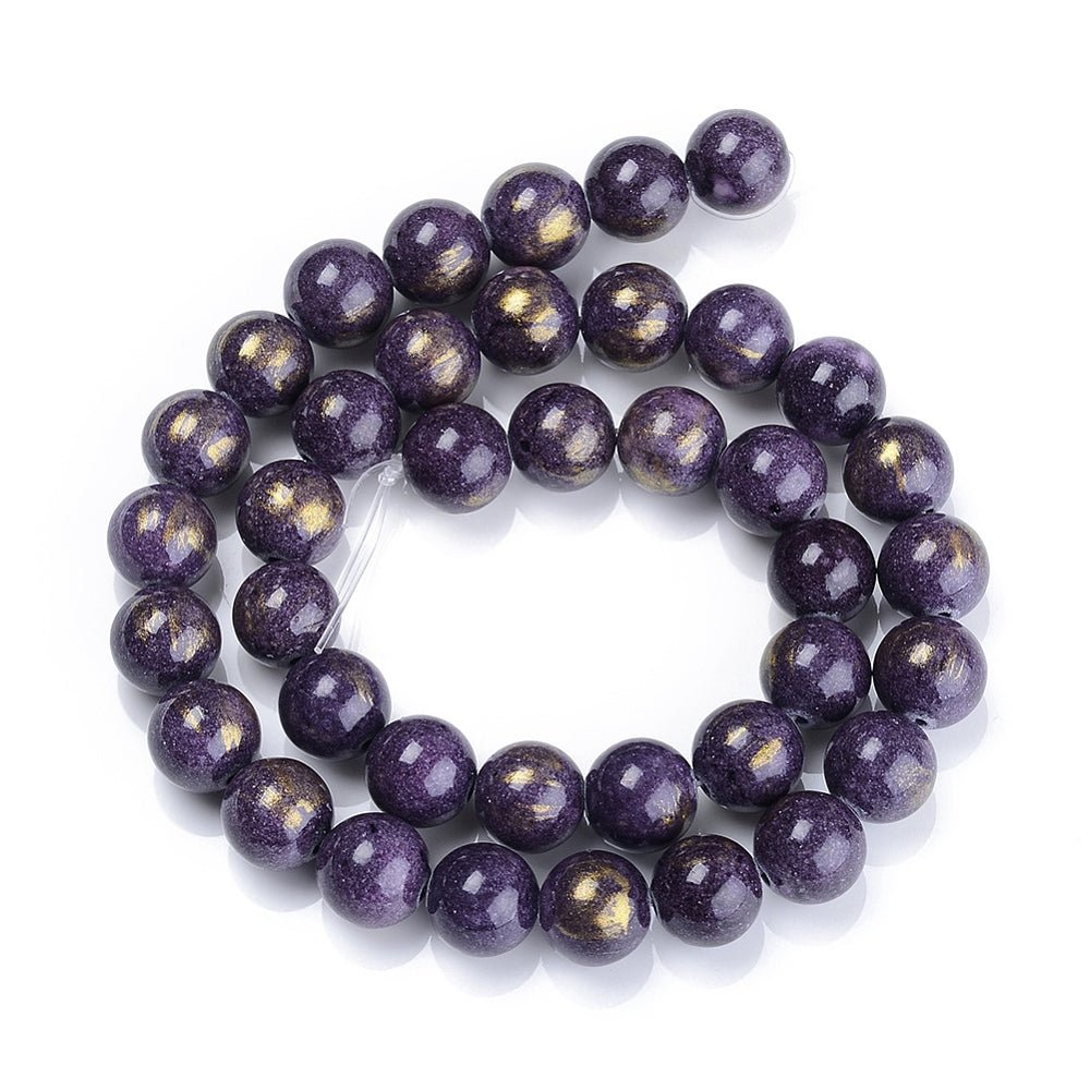 smooth round and dyed purple jade bead strand with gold foil in a swirl display over white surface. 